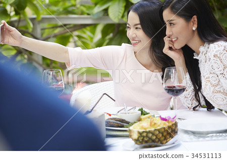 Two young women are making a sefie in a restaurant. 34531113