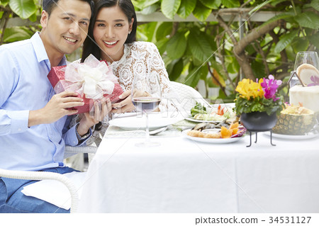 The couple is taking a photo with a gift in hand when having meal The couple is taking a photo with a gift in hand when having meal 34531127
