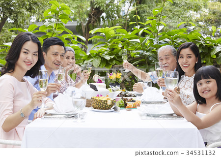 Extended family, parents, grandparents and child, eating outdoors 34531132
