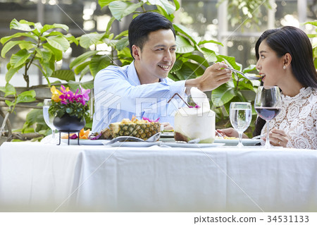 The couple is sitting and feeding each other at a restaurant 34531133