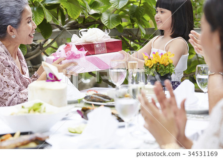 Everyone are clapping when the little girl is receiving gifts from her grandmother 34531169