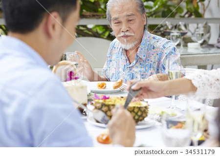 an old man is picking up food from a plate by fork in a restaurant 34531179