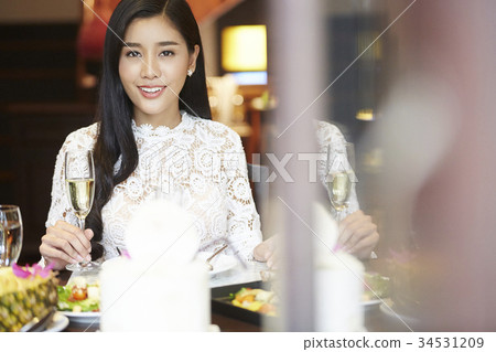 a good-looking woman is holding glass of wine and smiling in the dining room a good-looking woman is holding glass of wine and smiling in the dining room 34531209