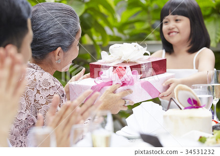 an adorable girl is giving gifts to her grandmother in her anniversary an adorable girl is giving gifts to her grandmother in her anniversary 34531232