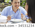 a handsome man is smiling and eating with his wife in a restaurant 34531234