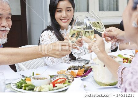 a young asian woman is having dinner and cheering up with family in a restaurant a young asian woman is having dinner and cheering up with family in a restaurant 34531235