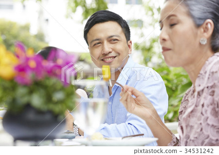 a healthy man is looking his mother while having breakfast in a restaurant 34531242