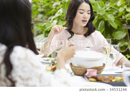 a gentle woman with curly hair is having meal with friends at a restaurant a gentle woman with curly hair is having meal with friends at a restaurant 34531246