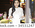 a woman with floral shirt is smiling and eating in a luxurious restaurant 34531247