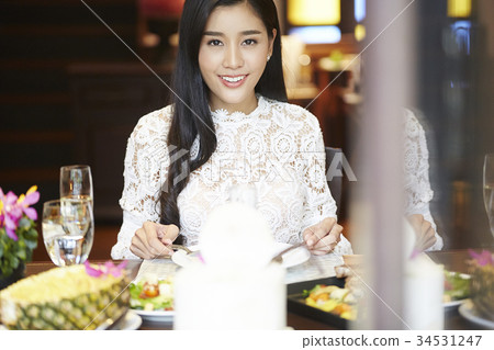 a woman with floral shirt is smiling and eating in a luxurious restaurant a woman with floral shirt is smiling and eating in a luxurious restaurant 34531247