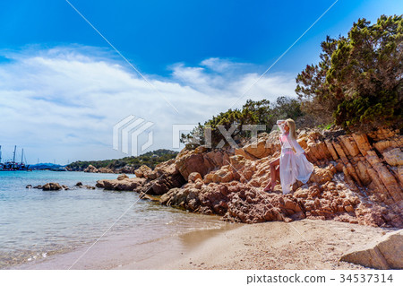 Beautiful woman sitting on a rock ocean shore 34537314