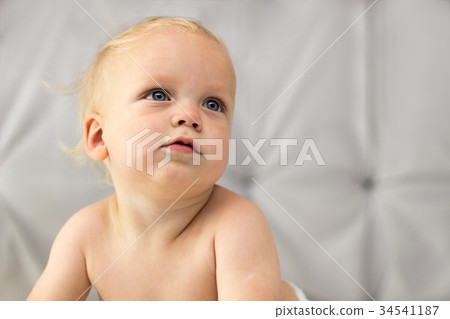 Cute thoughtful baby boy sitting on the bed 34541187