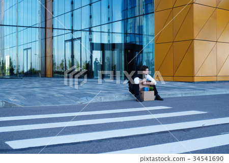 Fired businessman sitting on street Fired businessman sitting on street 34541690