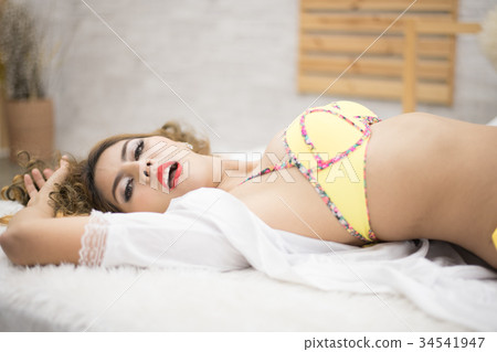 Woman in sexy yellow swimsuit poses in bedroom. Woman in sexy yellow swimsuit poses in bedroom. 34541947