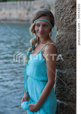 Young blonde woman with braided hear  wearing turquoise dress  34543850