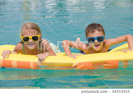 Two happy children playing on the swimming pool at the day time. Two happy children playing on the swimming pool at the day time. 34553453