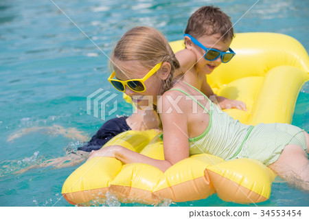 Two happy children playing on the swimming pool at the day time. Two happy children playing on the swimming pool at the day time. 34553454