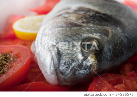 raw bream with tomatoes and lemon in a dish raw bream with tomatoes and lemon in a dish 34556575