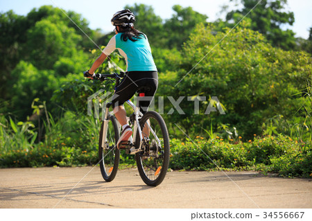 woman cyclist cycling on summer forest trail 34556667