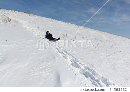 Man riding a mountain on a sled in winter Man riding a mountain on a sled in winter 34563382