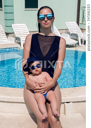 sexy young mother sitting near the pool with his sexy young mother sitting near the pool with his 34566283