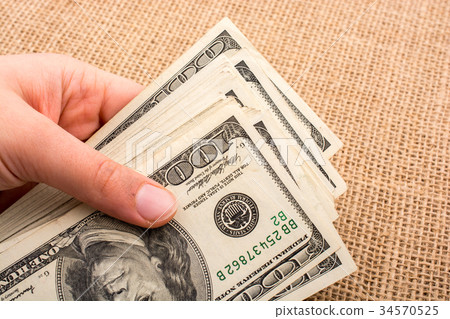 Hand holding banknote bundle of US dollar in hand Hand holding banknote bundle of US dollar in hand 34570525