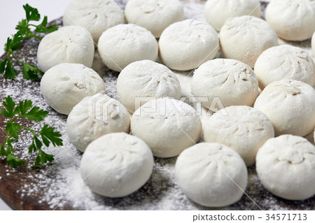 Khinkali on wooden plate with flour. Pelmeni 34571713