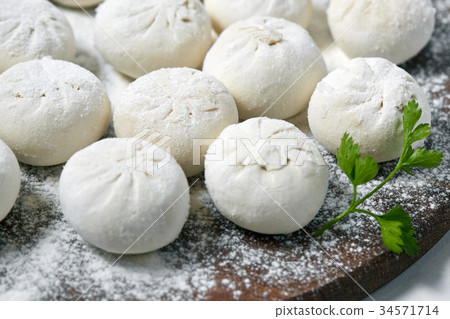 Khinkali on wooden plate with flour. Pelmeni 34571714