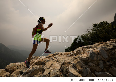 woman trail runner running up top of mountain 34573705