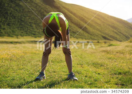 tired young woman runner have a rest on grassland  34574209