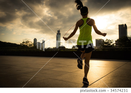 fitness woman jumping rope at sunrise city  34574231