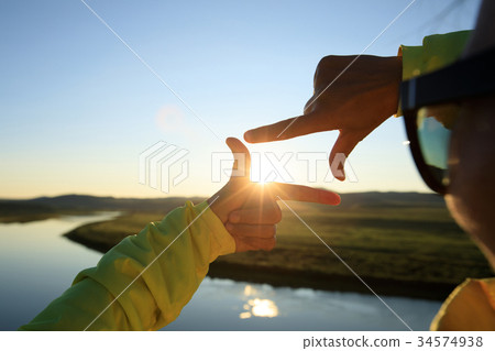 hands making a frame sign over sunset sky hands making a frame sign over sunset sky 34574938