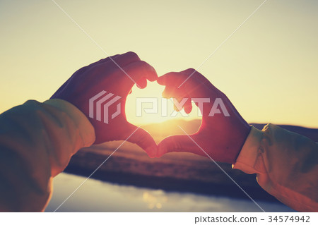 hands making Heart shaped sign over sunset sky hands making Heart shaped sign over sunset sky 34574942