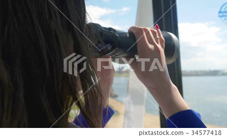 Woman is looking through binoculars while rides on Woman is looking through binoculars while rides on 34577418