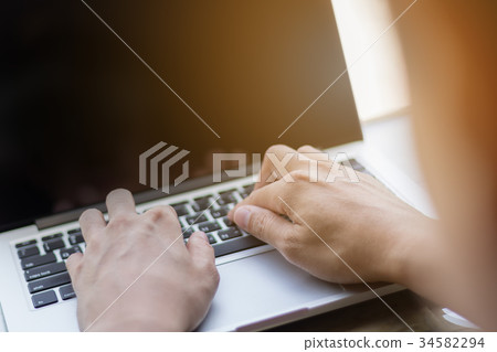 Hands typing on laptop in coffee shop Hands typing on laptop in coffee shop 34582294