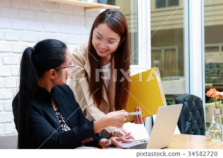 Two business women are discussing work. Two business women are discussing work. 34582720