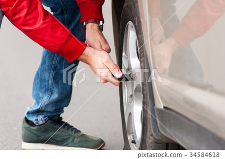 Male driver changing spare wheel on cityroad Male driver changing spare wheel on cityroad 34584618