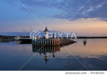 Small lighthouse and sailing boats at sunset. Small lighthouse and sailing boats at sunset. 34590383