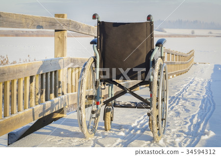 Wheelchair on bridge near lake in winter Wheelchair on bridge near lake in winter 34594312