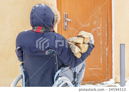 Disabled man on wheelchair near door with firewood Disabled man on wheelchair near door with firewood 34594313