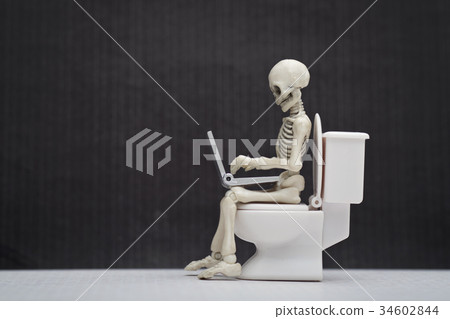 A skeleton and laptop on water closet 34602844
