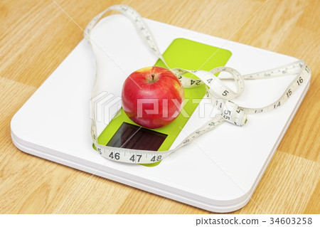 Apple with measuring tape on electronic scale.Diet Apple with measuring tape on electronic scale.Diet 34603258