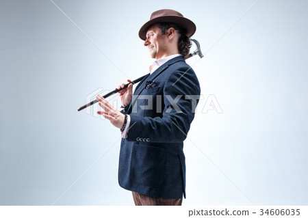 The mature man in a suit and hat holding cane. 34606035