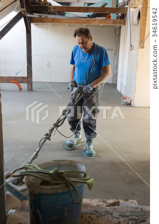Laborer polishing sand and cement screed floor. 34619542