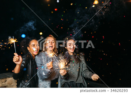 Three happy women having fun with sparklers Three happy women having fun with sparklers 34620293