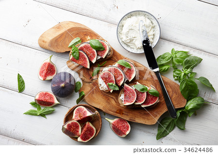 Fresh figs, basil and cream cheese bruschetta on white table 34624486