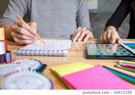 Two young dressmaker or designer colleagues working as fashion d 34625589