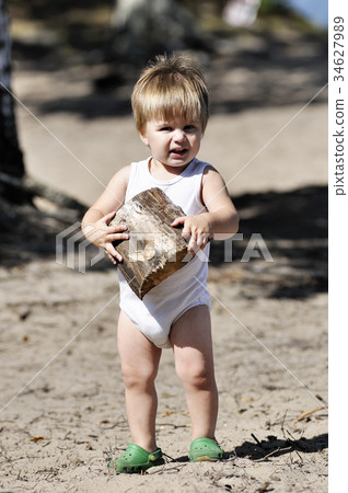 Happy little child plays with chopped billet 34627989