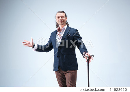 The mature barded man in a suit holding cane. The mature barded man in a suit holding cane. 34628630