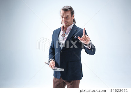 The mature barded man in a suit holding cane. 34628651